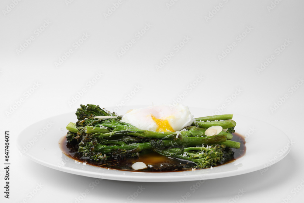 Tasty cooked broccolini with poached egg, almonds and sauce on white background, closeup Tasty cooked broccolini with poached egg, almonds and sauce on white background, closeup
