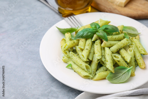 Delicious pasta with pesto sauce and basil on light grey table, closeup. Space for text