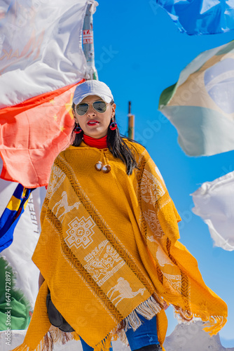 Brunette girl trekking with a traditional yellow hand-woven poncho in the Andes mountain of Bolivia Salar de Uyuni, Incahuasi - Trail of the Incas