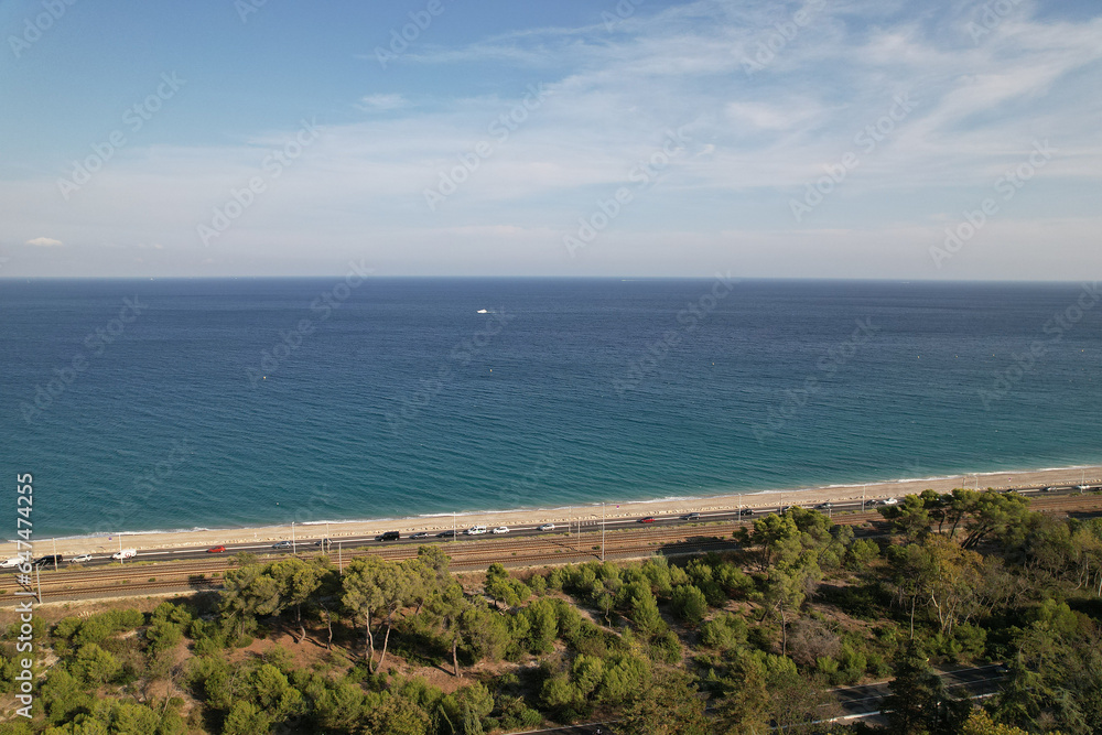Aerial photography. View over the trees of Vaugrenier Park in the city of Villeneuve-Loubet-Plage France, a road with cars and the Mediterranean Sea.