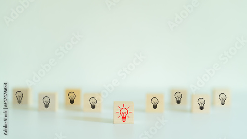 A wooden cube with a red light bulb symbol on the front. innovative new concept and problem solving concepts Being a leader in the organization Success in business