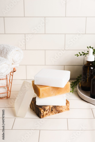 Handmade organic bar soaps on white tile background. Sustainable zero-waste lifestyle with serum bottles and bath accessories. Copy space for your text © romanovad