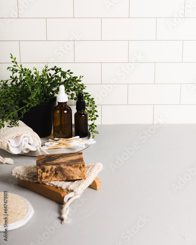 Handmade organic bar soaps on white tile background. Sustainable zero-waste lifestyle with serum bottles and bath accessories. Copy space for your text © romanovad