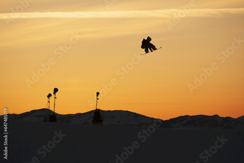 Silhouette Of A Snowboarder Jump In Mid-Air At Sunset; Norway photo