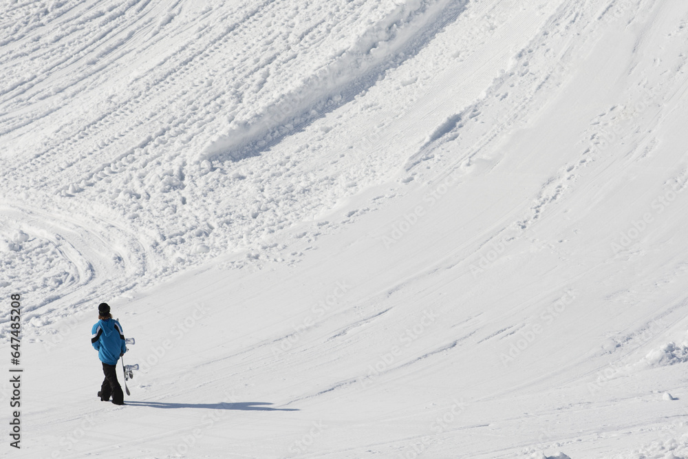 Snowboarder Walks With Snowboard At The Base Of A Mountain; Norway Snowboarder Walks With Snowboard At The Base Of A Mountain; Norway