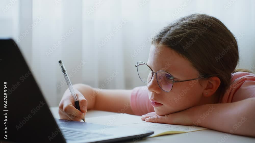 Tired teenage schoolgirl looking at laptop Tired teenage schoolgirl looking at laptop