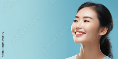 portrait of a beautiful woman and smiling with clean teeth and perfect skin isolated on light blue background, for spa advertising, copy space