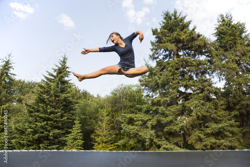 Teenage Girl Jumping High In The Air Outdoors On A Trampoline; Sherwood Park, Alberta, Canada photo