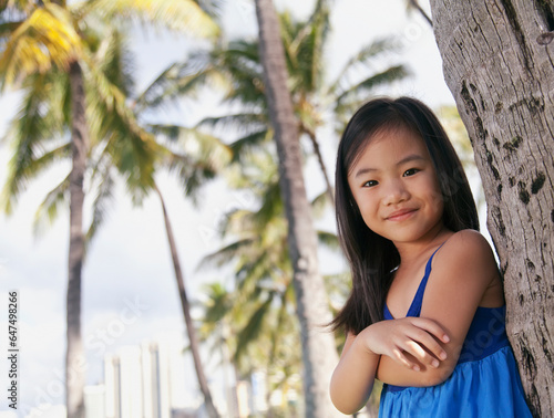 Portrait of a young girl leaning against the trunk of a tree; Honolulu oahu hawaii united states of america photo