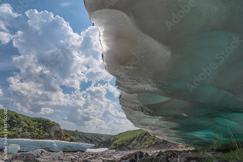 View under an overhang of late season ice known as aufeis along a stream in summer, Yukon, Canada photo