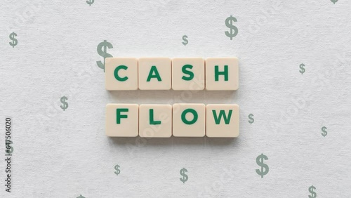 Green Dollar Signs Going Up Behind The Cash Flow Shown On Scrabble Blocks. photo