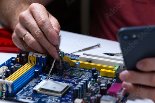 A technician repairs a motherboard in a service center. Computer Repair