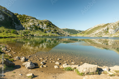 A beautiful mountain landscape of the Lagos de Covadonga or Lakes in the Picos de Europa in Spain. The perfect reflection of the mountains on the rocky shoreline completed this panoramic view.