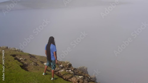 Man gazing into foggy horizon, standing on cliff. Inishbofin, Ireland photo