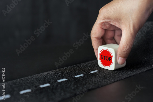 Φωτογραφία Red stop cube wooden in hand at the dead end street with black background