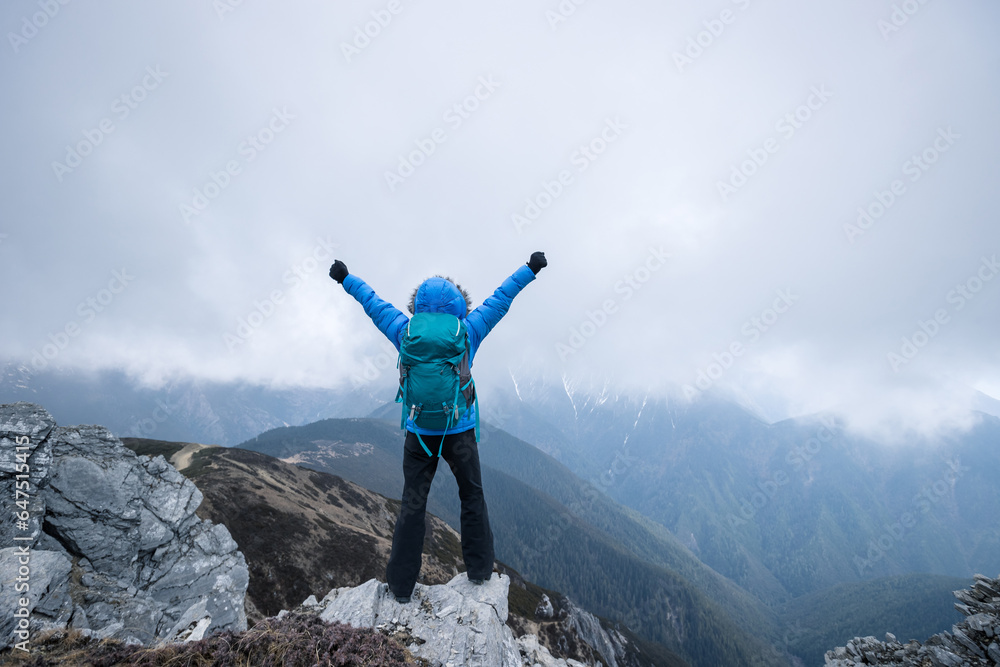 Woman hiker enjoy the view on mountain top cliff edge face the snow capped mountains in tibet Woman hiker enjoy the view on mountain top cliff edge face the snow capped mountains in tibet
