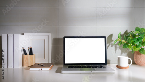 Laptop computer, coffee cup, potted plant and picture frame on creative workplace. Blank screen for your advertising text. © wattana