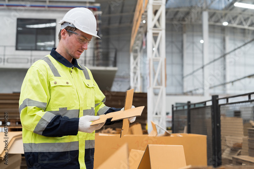 Male warehouse worker working and inspecting quality of cardboard in corrugated carton boxes warehouse storage