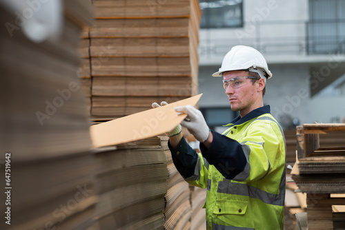 Male warehouse worker working and inspecting quality of cardboard in corrugated carton boxes warehouse storage