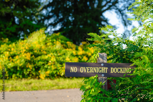 Weathered brown and gold wood sign on post, NO OVERNIGHT DOCKING. 