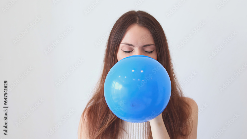 A beautiful woman inflates a blue balloon. A beautiful woman inflates a blue balloon.