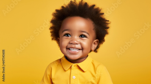 Portrait of a toddler posing against a yellow background. happy smiling boy