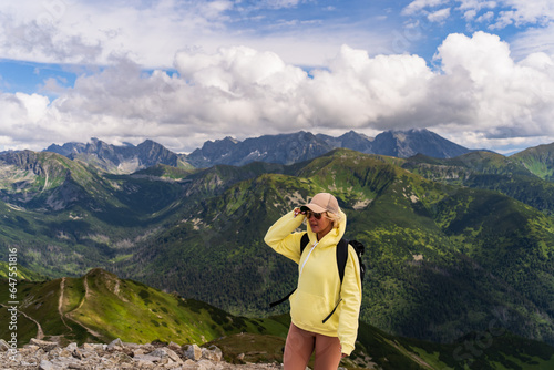 A young girl hiker high in the Polish Tatra mountains near a cliff on a summer evening, the sky is overcast.