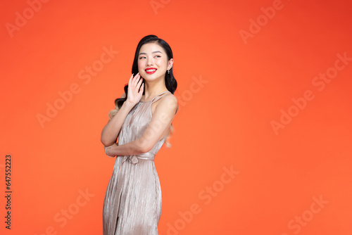 attractive pretty woman in shiny festive dress looking at camera and smiling over isolated backdrop