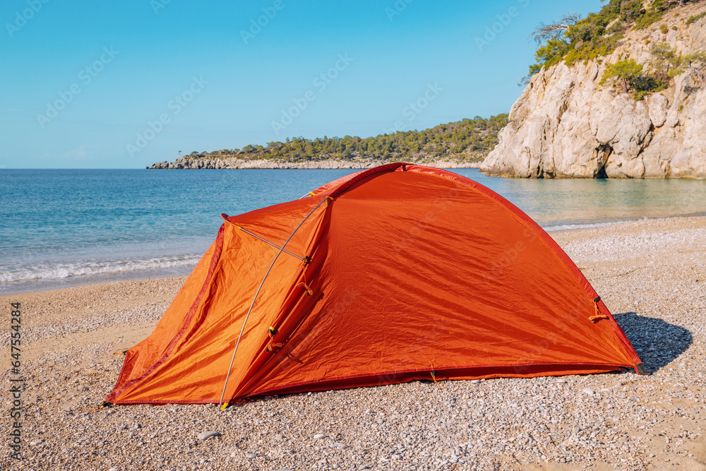 Orange tent set up of a sandy beach at long distance hiking trail - Lycian way or Camino de Santiago