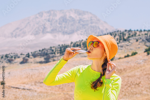 Obraz na płótnie Pretty young woman biting on a energy sportive gel drink after a good hike in high mountains w salonie