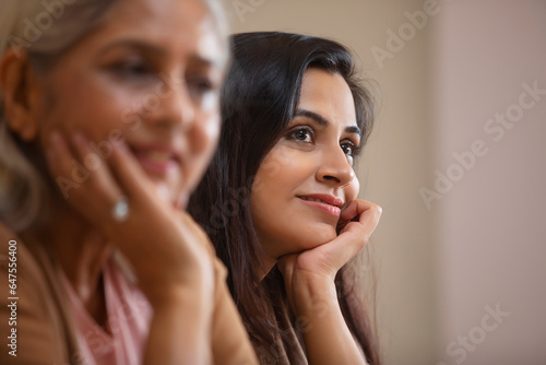 A YOUNG WOMAN SITTING AND THINKING WITH MOTHER SITTING AHEAD photo