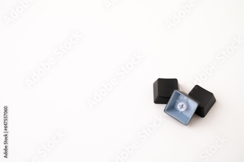 A close-up of a pile of three detached mechanical keyboard keycaps on a white isolated background. Copy space.
