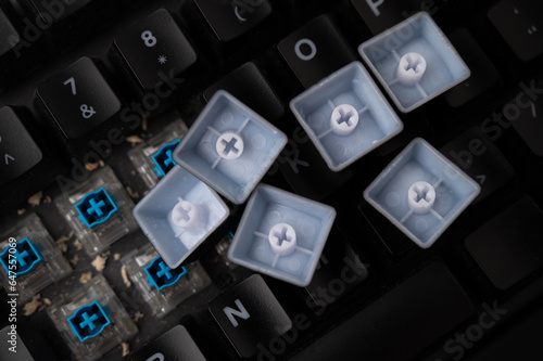 Close-up of a dirty mechanical keyboard with blue switches, with some keycaps removed and lot of debris visible.