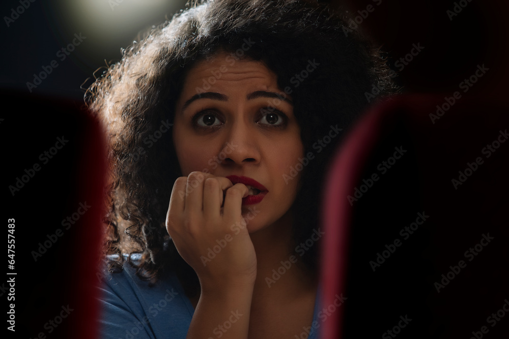 Portrait of a shocked and surprised woman while watching horror movie in the movie theater Portrait of a shocked and surprised woman while watching horror movie in the movie theater