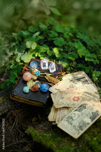 witch book with set of minerals, vintage divination cards in forest, natural background. Gemstones for Magic Crystal Ritual. Witchcraft, spiritual esoteric practice. stone therapy, tarot reading.