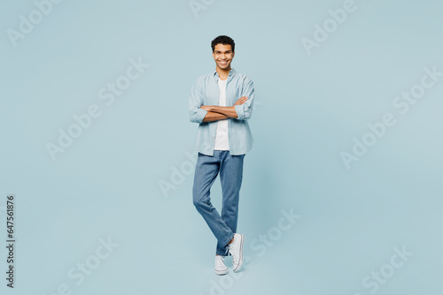 Full body smiling happy cheerful young man of African American ethnicity he wearing shirt casual clothes hold hands crossed folded isolated on plain pastel light blue cyan background studio portrait.