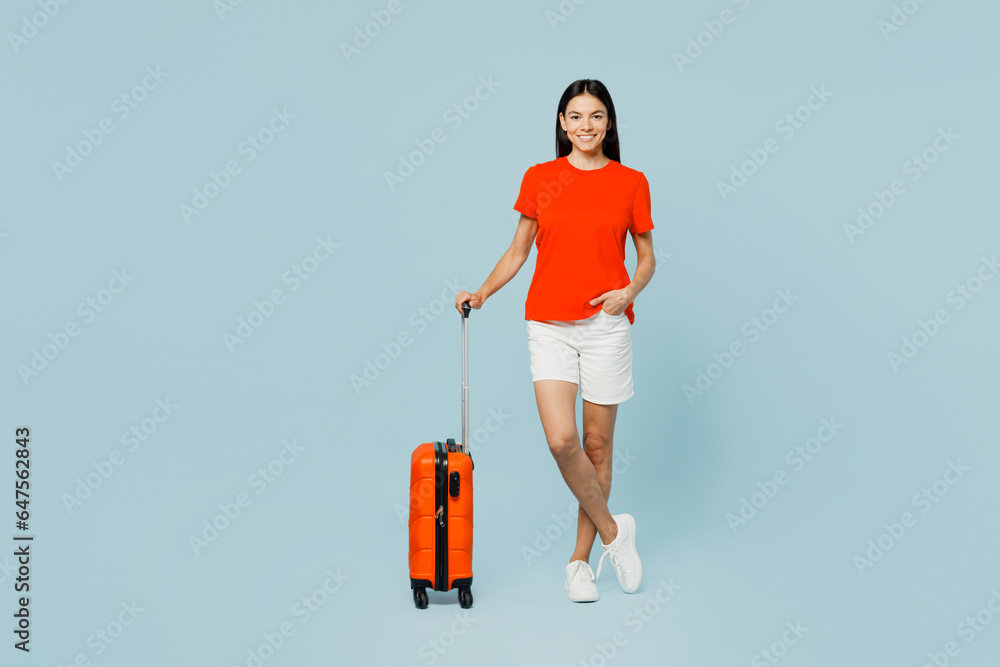 Traveler latin woman wearing casual clothes hold suitcase look camera isolated on plain pastel blue background. Tourist travel abroad in free spare time rest getaway. Air flight trip journey concept. Traveler latin woman wearing casual clothes hold suitcase look camera isolated on plain pastel blue background. Tourist travel abroad in free spare time rest getaway. Air flight trip journey concept.