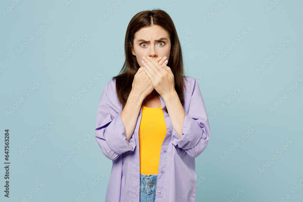 Young sad shocked scared woman she wears purple shirt yellow t-shirt casual clothes look camera cover mouth woth hands isolated on plain pastel light blue background studio portrait Lifestyle concept Young sad shocked scared woman she wears purple shirt yellow t-shirt casual clothes look camera cover mouth woth hands isolated on plain pastel light blue background studio portrait Lifestyle concept