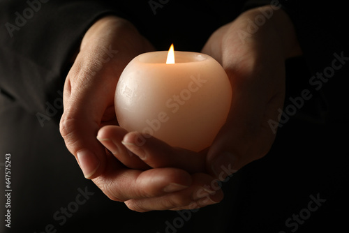 Mourning candles in hands, on a dark background.