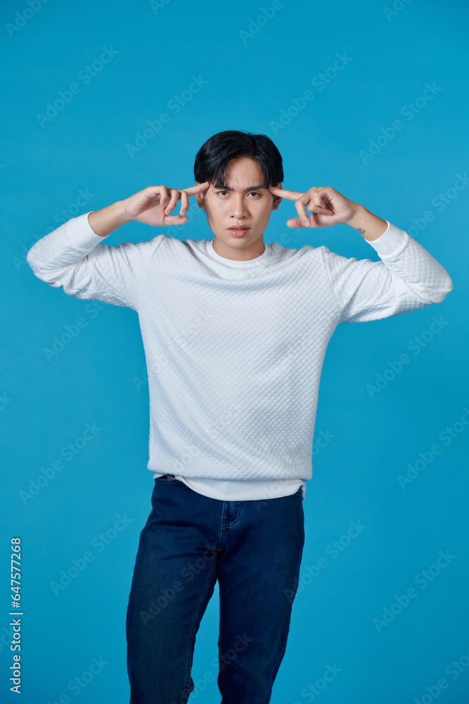 Asian man looking happy and posing as if thinking with his hand pointing to his head