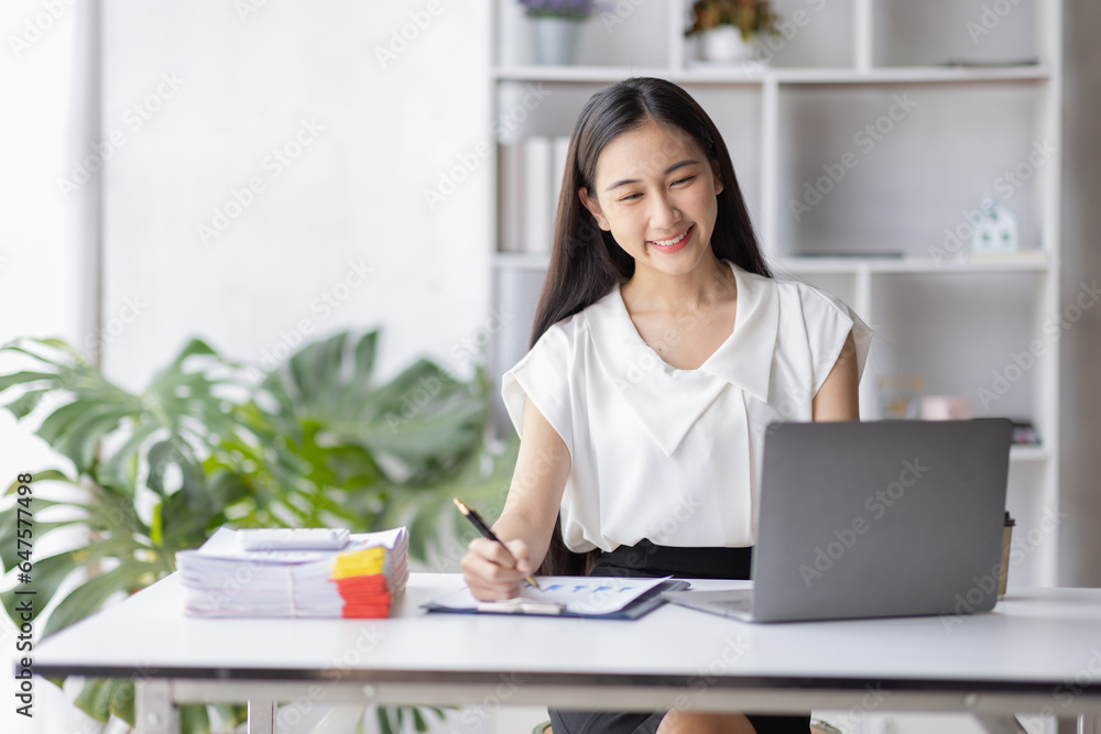 Happy young Asian girl working at a office with a laptop calculator to calculate business accounting statistics concept Happy young Asian girl working at a office with a laptop calculator to calculate business accounting statistics concept