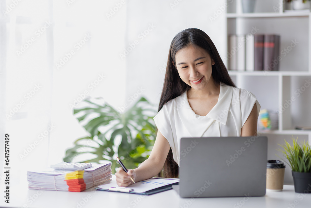 Happy young Asian girl working at a office with a laptop calculator to calculate business accounting statistics concept Happy young Asian girl working at a office with a laptop calculator to calculate business accounting statistics concept