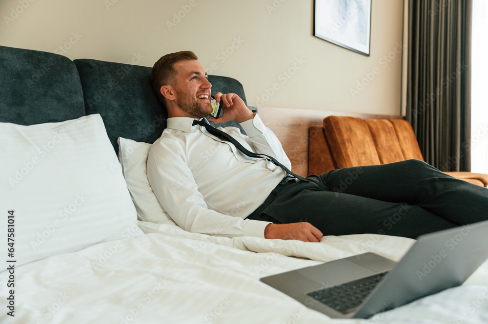 Talking by phone. Businessman is indoors in the hotel room