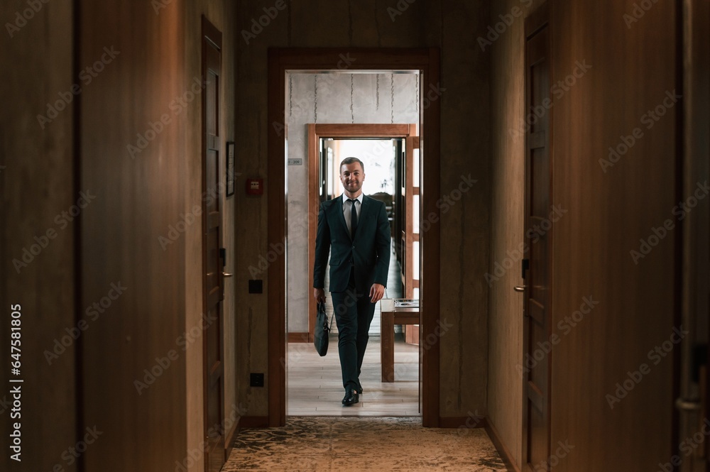 Front view, in the appartment. Handsome businessman is indoors in the hotel room Front view, in the appartment. Handsome businessman is indoors in the hotel room