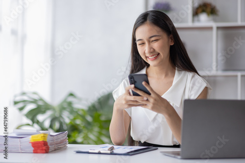 Young asian business woman using laptop and using phone note, woman officer hard working communicate with customer and record business employee concept