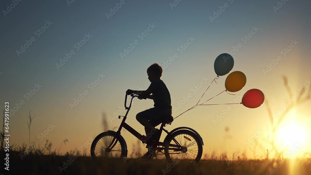 Obraz premium kid silhouette bike riding on a park. kid boy rides a bike in nature in the park on the road. happy family kid dream concept. son plays a bike rides on a lifestyle sandy road