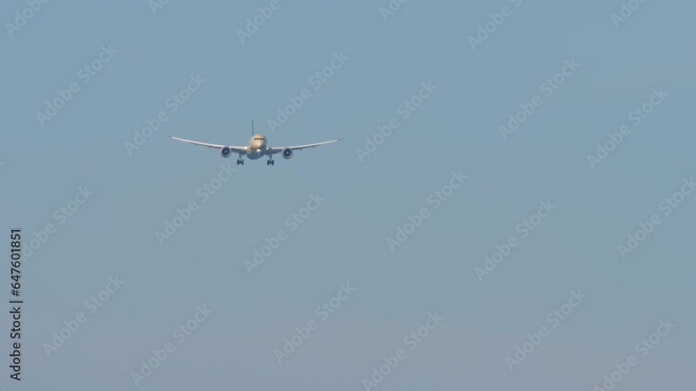 Shot, passenger airliner approaching for landing. Airplane with unrecognizable livery descending in the blue sky. Plane flies, front view. Tourism and travel concept Shot, passenger airliner approaching for landing. Airplane with unrecognizable livery descending in the blue sky. Plane flies, front view. Tourism and travel concept