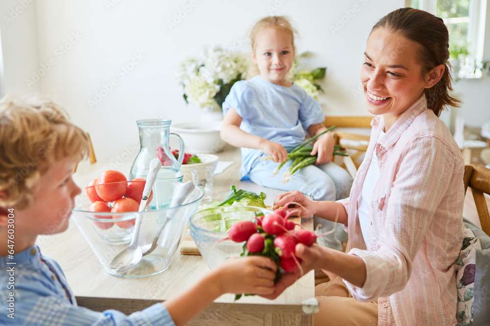 Smiling mother taking radish from son at home