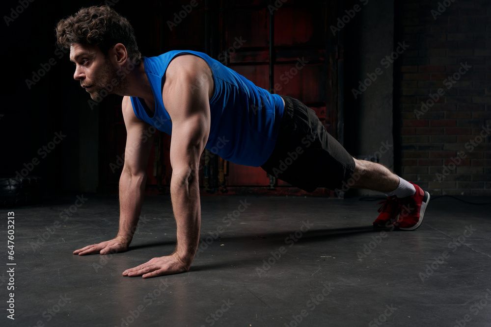 full length of strong man in sportswear training in plank pose in darkness of night street full length of strong man in sportswear training in plank pose in darkness of night street