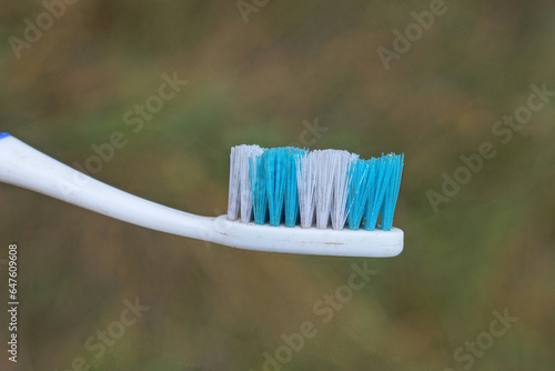 one old dirty plastic white blue toothbrush on the street on a gray background